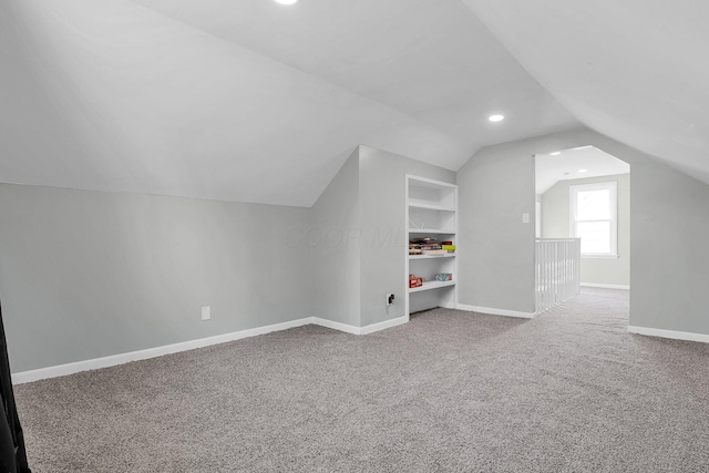 additional living space featuring lofted ceiling and carpet flooring