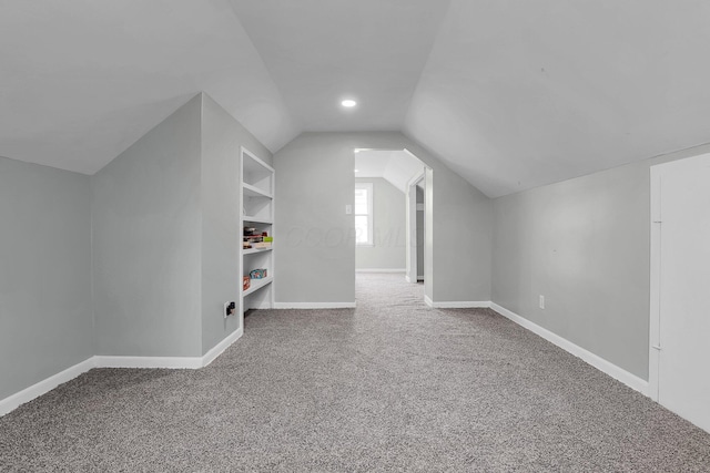 bonus room featuring lofted ceiling, carpet floors, and built in features