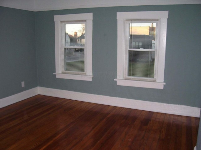 unfurnished room with dark wood finished floors and baseboards