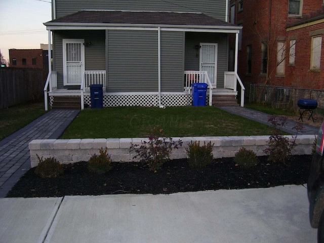 view of front facade with a porch, a front yard, and fence