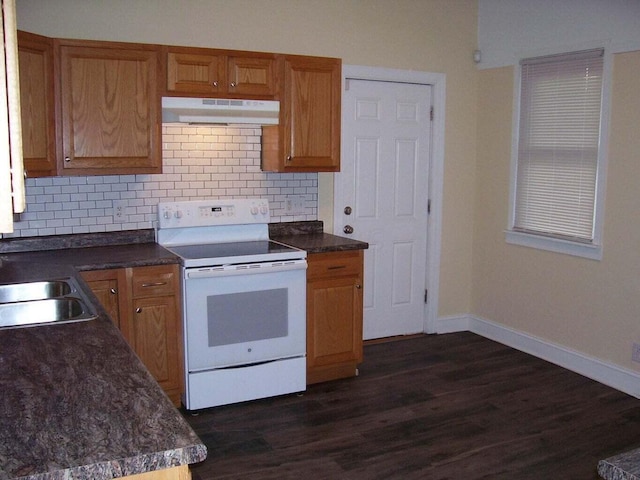 kitchen featuring white range with electric cooktop, a sink, under cabinet range hood, dark countertops, and tasteful backsplash