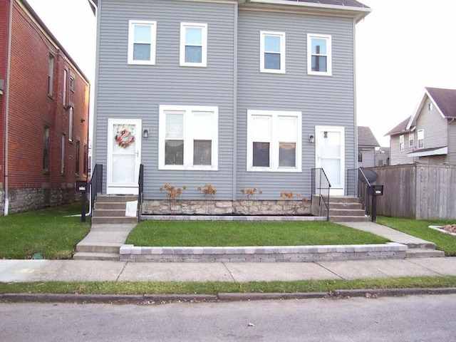 view of front of property featuring entry steps, a front lawn, and fence