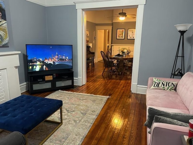 living room featuring ceiling fan, baseboards, and wood-type flooring