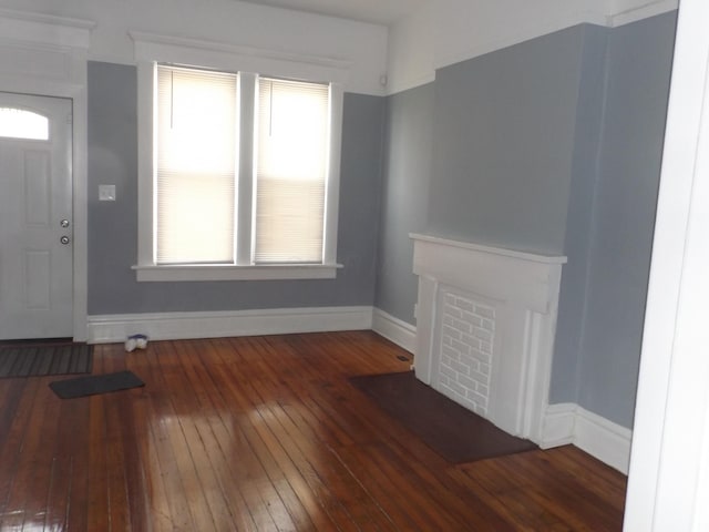 unfurnished living room with hardwood / wood-style floors and baseboards