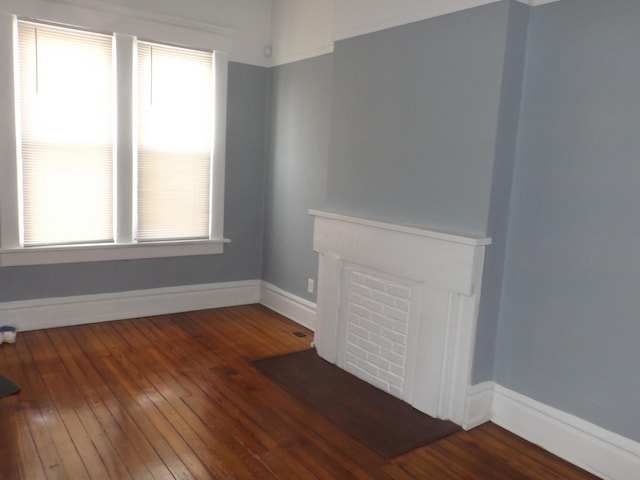 unfurnished living room with baseboards and wood-type flooring