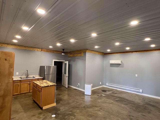 kitchen featuring an AC wall unit, sink, stainless steel fridge, a center island, and a baseboard heating unit