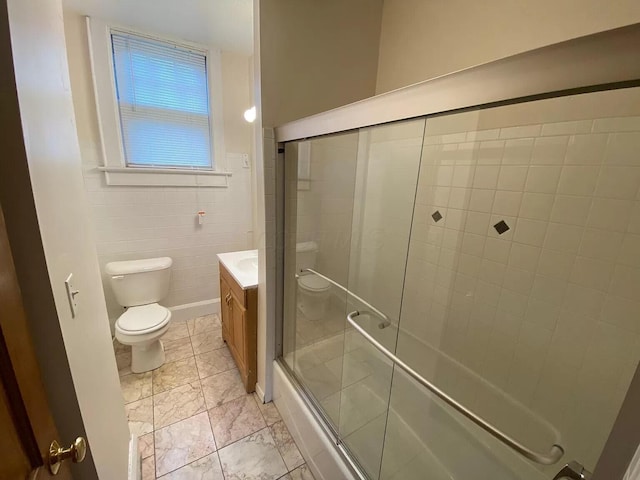 full bathroom featuring vanity, tile walls, shower / bath combination with glass door, and toilet