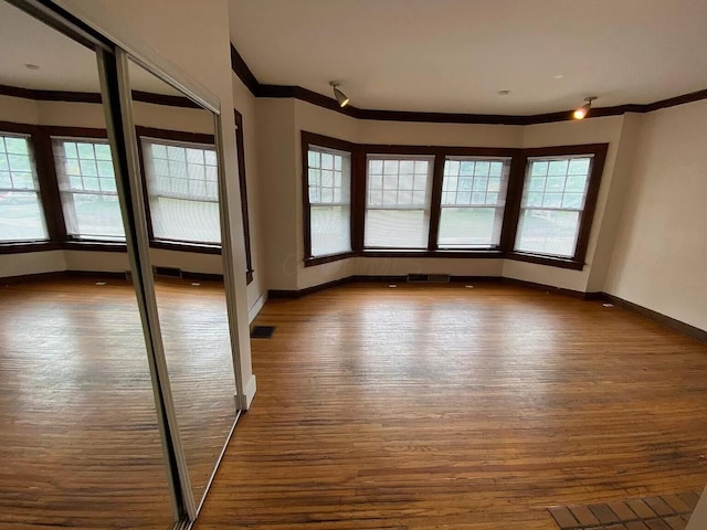 spare room with hardwood / wood-style floors and crown molding