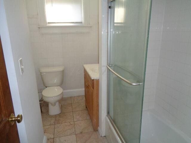 full bathroom featuring vanity, bath / shower combo with glass door, tile patterned floors, and toilet