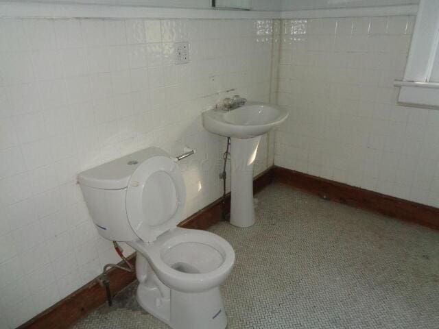 bathroom featuring toilet, sink, and tile walls