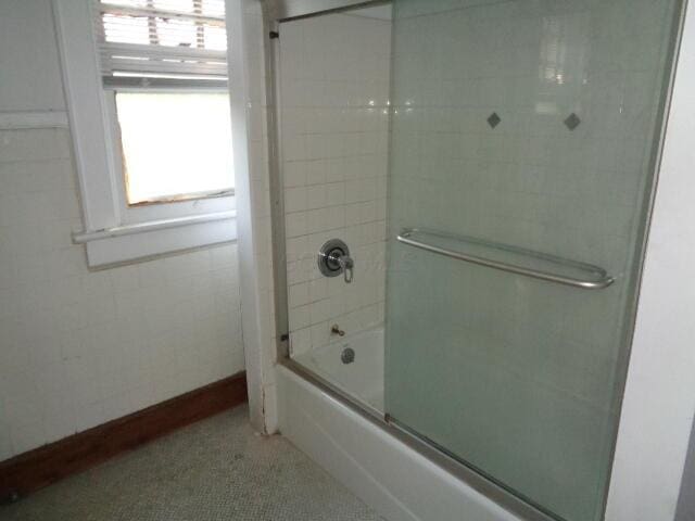 bathroom with bath / shower combo with glass door