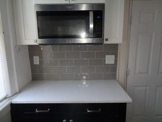 kitchen with tasteful backsplash and white cabinetry