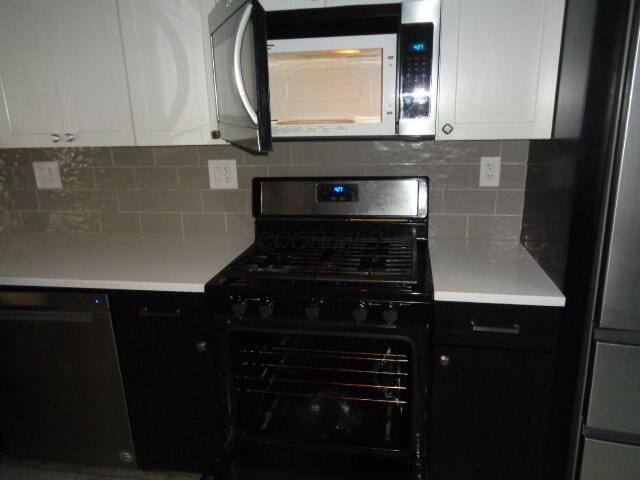 kitchen featuring white cabinetry, fridge, tasteful backsplash, and range with gas stovetop