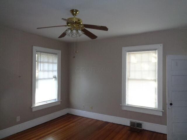 spare room with ceiling fan, a wealth of natural light, and dark hardwood / wood-style flooring