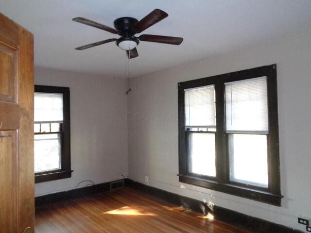 unfurnished room with ceiling fan and dark hardwood / wood-style flooring