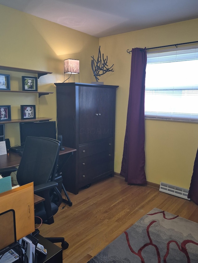 home office featuring a baseboard heating unit and wood finished floors