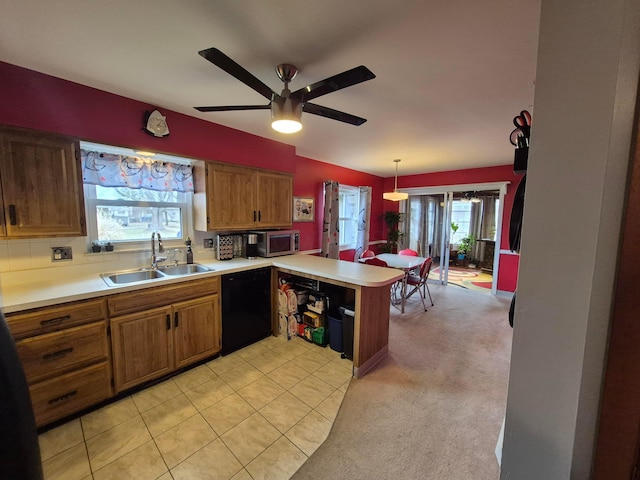 kitchen with a peninsula, a sink, brown cabinetry, dishwasher, and stainless steel microwave