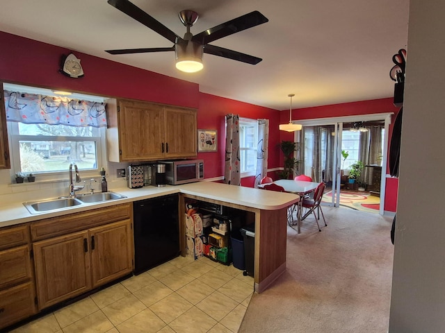 kitchen featuring a peninsula, a sink, black dishwasher, brown cabinets, and stainless steel microwave