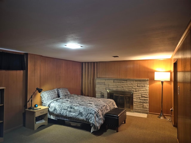 bedroom with carpet floors, wooden walls, and a fireplace