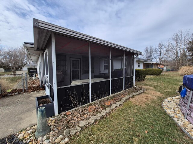 view of property exterior featuring a sunroom, a yard, and fence