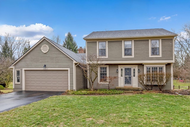 colonial house with an attached garage, driveway, and a front lawn