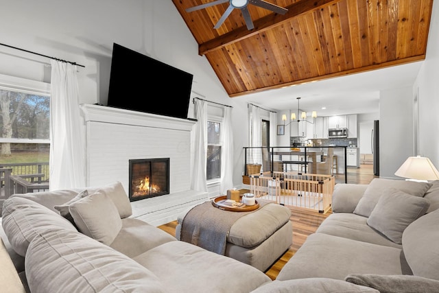 living area with high vaulted ceiling, a fireplace, wood ceiling, light wood-type flooring, and beamed ceiling