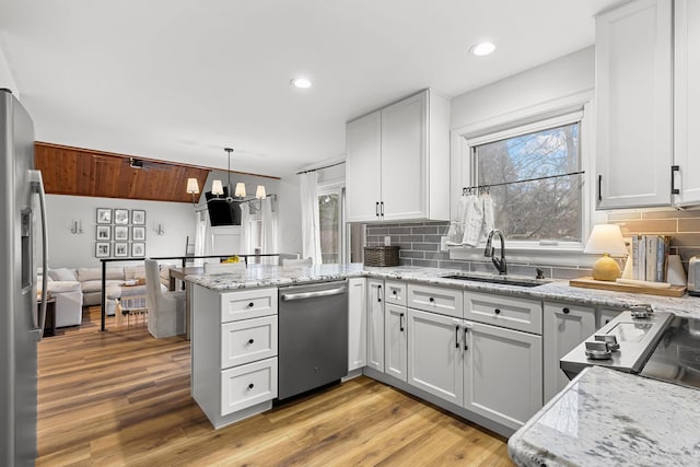 kitchen featuring a chandelier, a peninsula, a sink, appliances with stainless steel finishes, and plenty of natural light