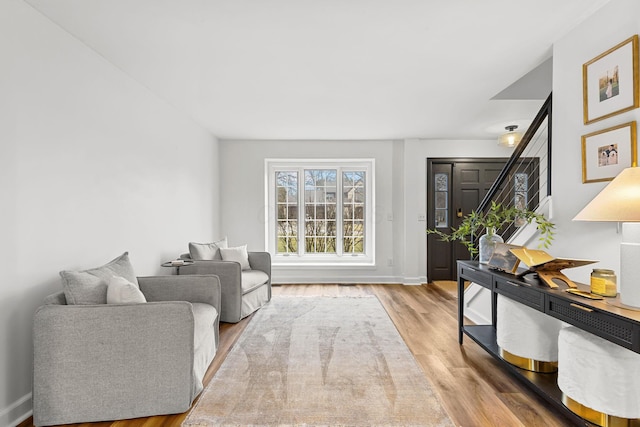 sitting room featuring stairway, wood finished floors, and baseboards