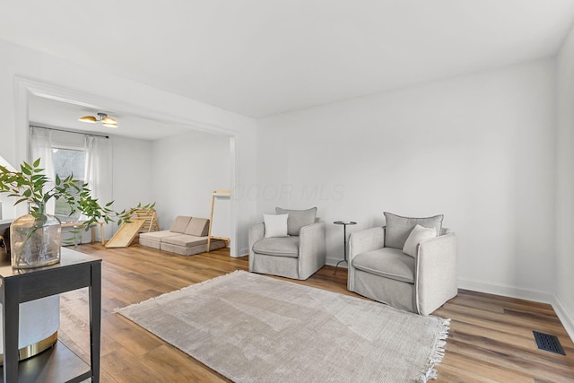 living area with wood finished floors, visible vents, and baseboards