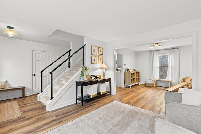 living area featuring wood finished floors, baseboards, and stairs