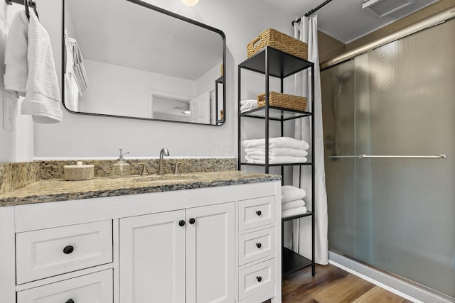 full bathroom featuring visible vents, a shower with door, vanity, and wood finished floors