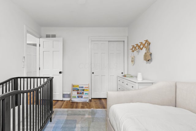 bedroom with a closet, visible vents, and wood finished floors