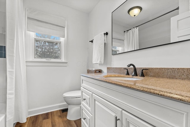 bathroom featuring toilet, baseboards, wood finished floors, and vanity