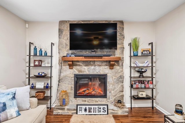 living room with a stone fireplace and dark wood-type flooring