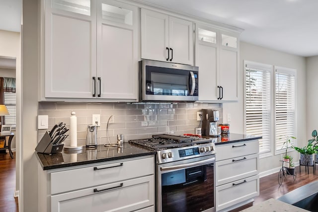 kitchen featuring tasteful backsplash, dark stone countertops, dark hardwood / wood-style flooring, stainless steel appliances, and white cabinets