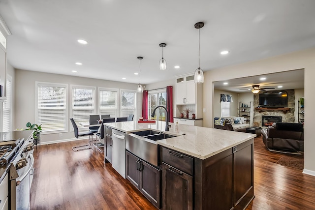 kitchen featuring pendant lighting, a fireplace, sink, dark brown cabinetry, and stainless steel appliances