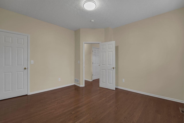 unfurnished room with a textured ceiling and dark hardwood / wood-style flooring