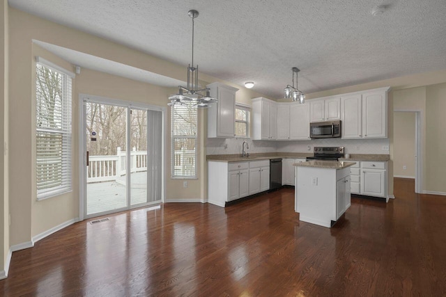 kitchen with a kitchen island, electric range oven, decorative light fixtures, black dishwasher, and white cabinets