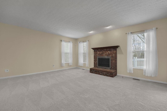 unfurnished living room featuring a fireplace, light colored carpet, and a textured ceiling