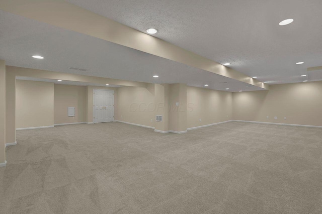 basement featuring light carpet and a textured ceiling