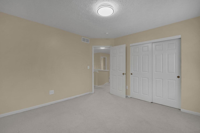 unfurnished bedroom featuring light colored carpet, a closet, and a textured ceiling