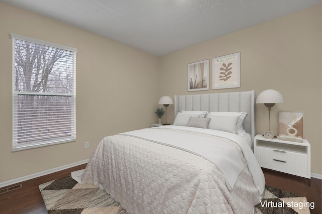 bedroom with dark hardwood / wood-style floors and a textured ceiling