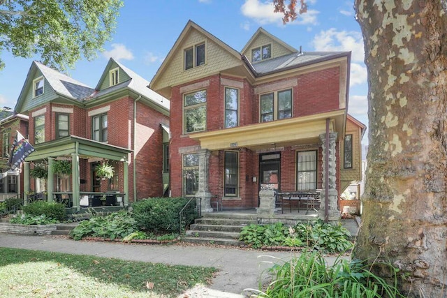 victorian-style house featuring a porch and brick siding