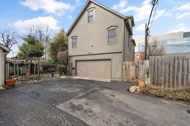 view of side of property with an attached garage, fence, and aphalt driveway