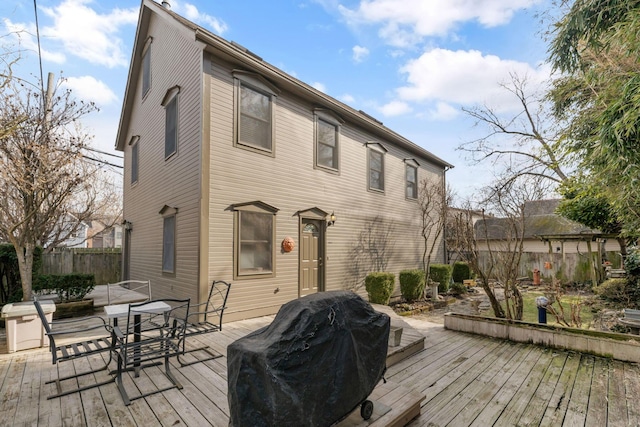 rear view of property featuring outdoor dining space, fence, and a deck