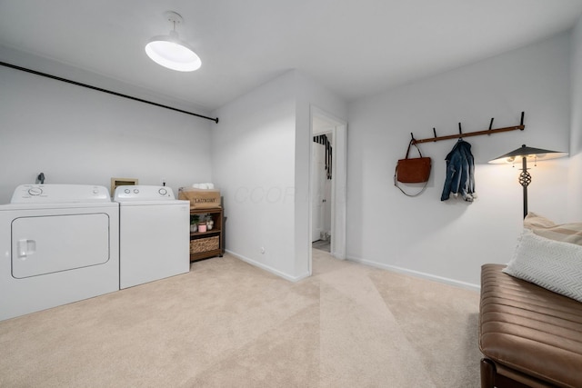 laundry area featuring washing machine and dryer, laundry area, light carpet, and baseboards