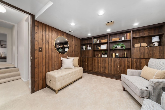 living area with recessed lighting, visible vents, stairway, light carpet, and wood walls