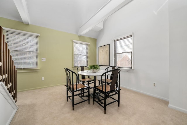 dining space featuring light colored carpet, vaulted ceiling with beams, and baseboards