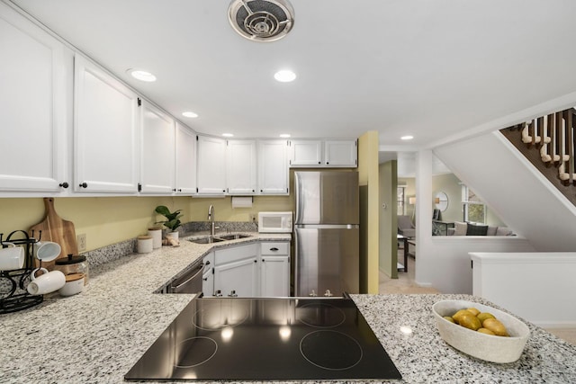 kitchen with stainless steel appliances, a sink, visible vents, white cabinetry, and light stone countertops