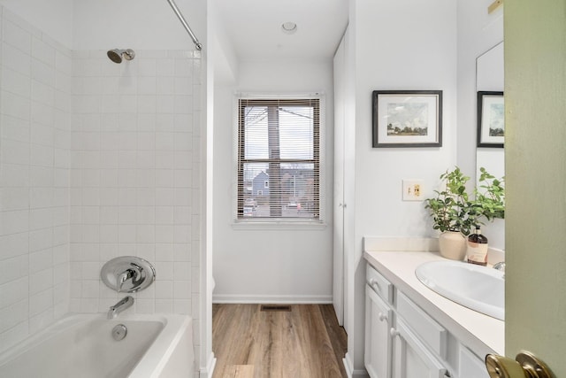 full bath featuring wood finished floors, visible vents, vanity, baseboards, and  shower combination